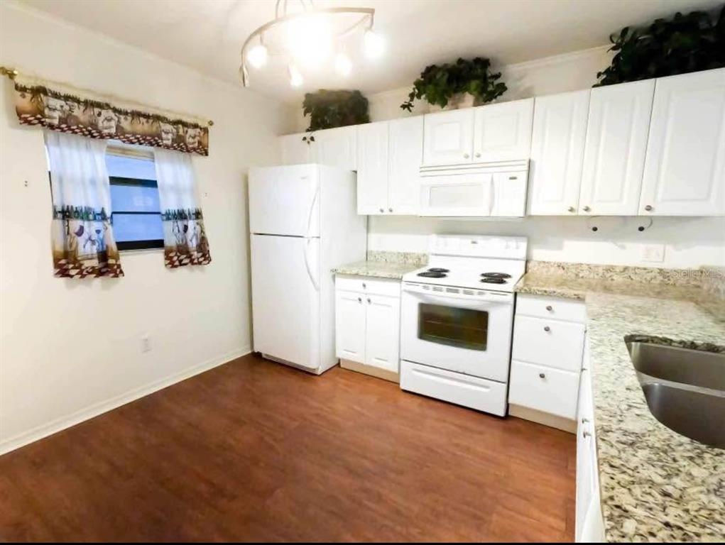 A kitchen features white cabinets, white appliances, granite countertops, and wood-look flooring — 175 KINGS HIGHWAY UNIT B5, PUNTA GORDA, FL
