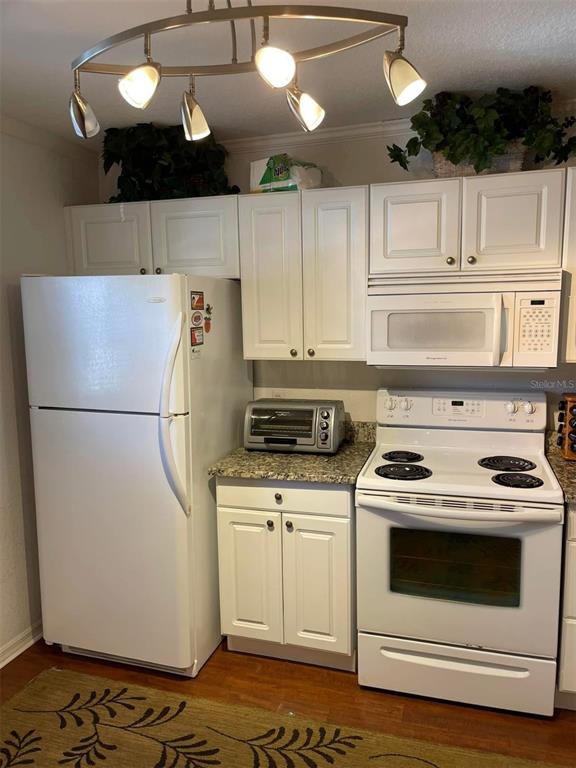 A kitchen features white cabinets, white appliances, a granite countertop, and a modern light fixture — 175 KINGS HIGHWAY UNIT B5, PUNTA GORDA, FL
