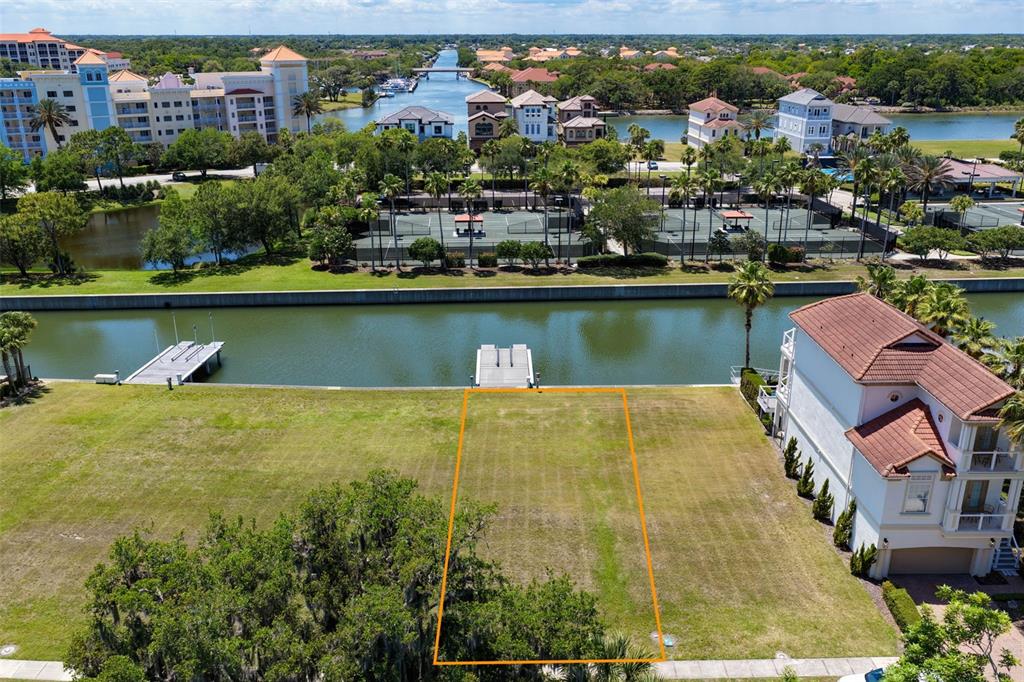 An aerial view shows a vacant waterfront lot outlined in orange next to a house — 216 HARBOR VILLAGE POINT N, PALM COAST, FL