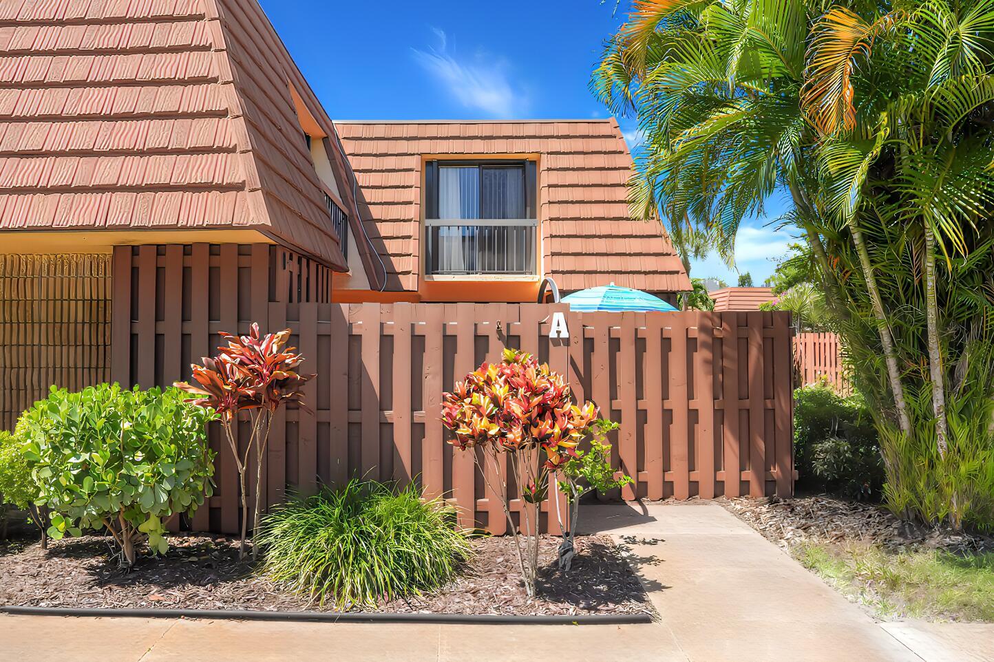 A brown wooden fence surrounds the front patio of a house with a tiled roof — 825 Center Street # 14a, Jupiter FL 33458, JUPITER, FL
