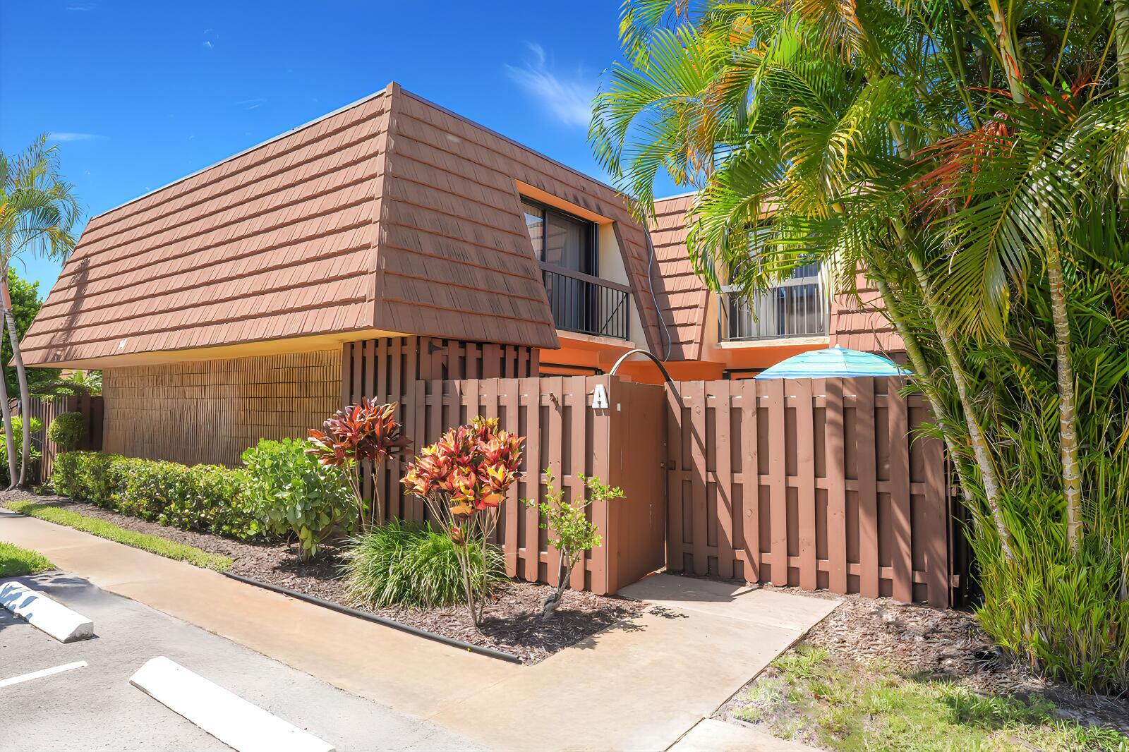 Exterior view of a two-story townhouse with a brown mansard roof and a wooden fence — 825 Center Street # 14a, Jupiter FL 33458, JUPITER, FL