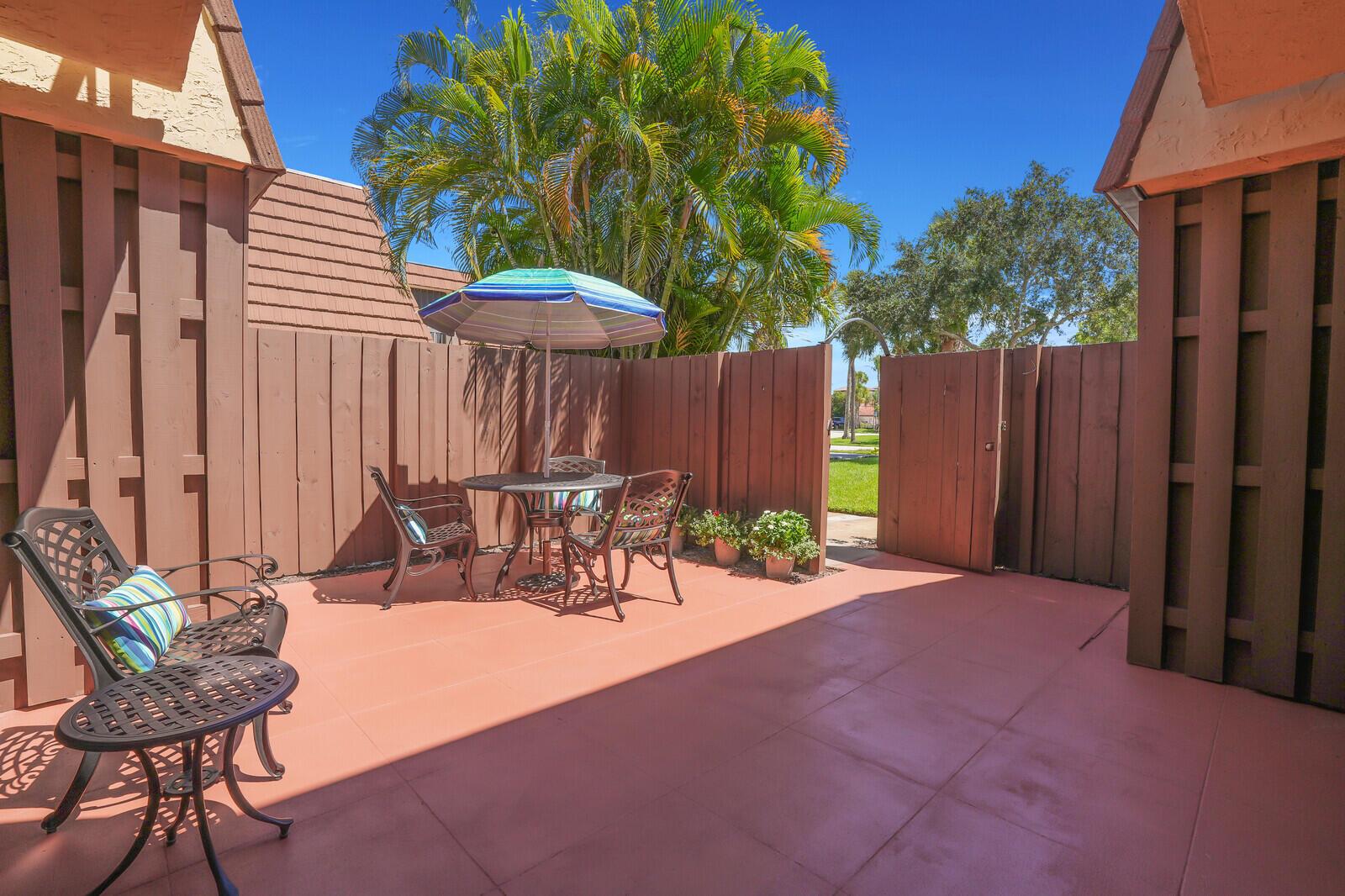 A private outdoor patio features a dining set with an umbrella and terracotta-colored tile flooring — 825 Center Street # 14a, Jupiter FL 33458, JUPITER, FL