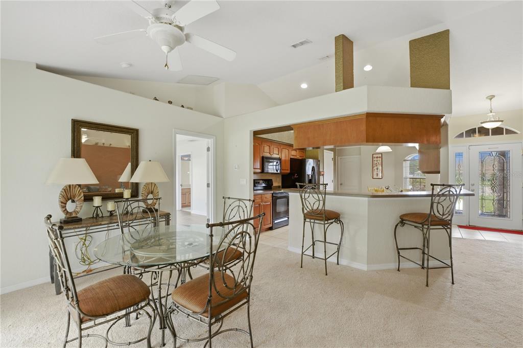 A dining area with a glass table and chairs sits before a kitchen breakfast bar — 3119 KEYSTONE POINTE COURT, ST CLOUD, FL