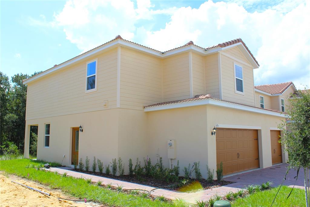 A two-story house with beige stucco and siding, a tile roof, and a two-car garage — 575 BAY LEAF DRIVE, POINCIANA, FL