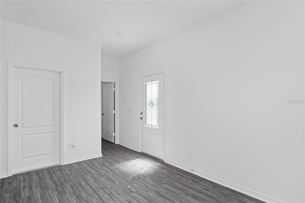 An interior view of a room with white walls, gray wood-look flooring, and two doors — 575 BAY LEAF DRIVE, POINCIANA, FL
