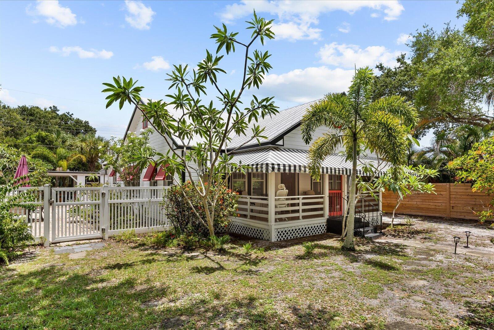 A white cottage with a striped awning over a porch and a white picket fence — 705 SE Stypmann Boulevard, Stuart FL 34994, STUART, FL