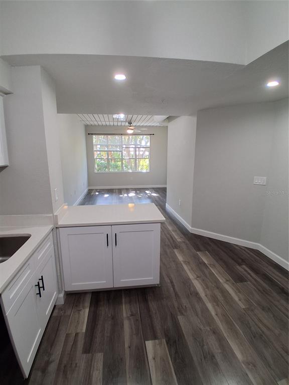 A kitchen with white cabinets and quartz countertops opens into a living area with wood-look flooring — 2402 W AZEELE STREET UNIT 417, TAMPA, FL