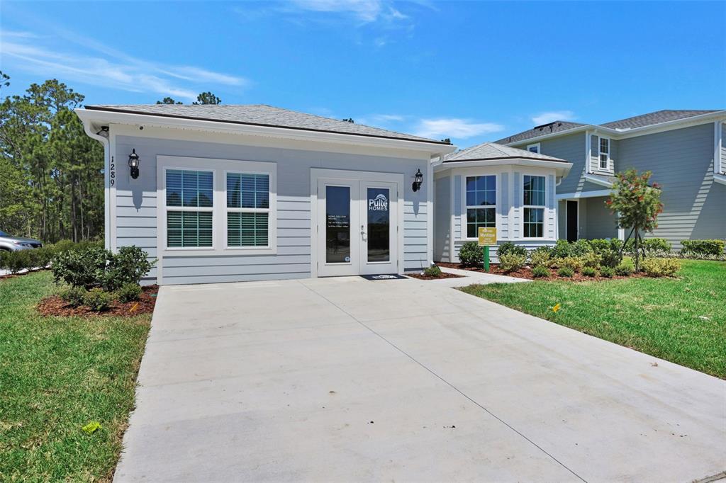 A light blue single-story building with a concrete driveway and a bay window — 82 LAKE MANATEE DRIVE, PALM COAST, FL