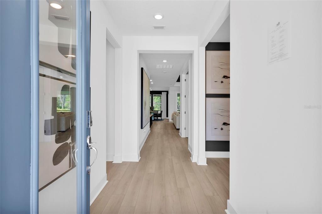 A view from a blue front door into a bright hallway with light wood flooring — 82 LAKE MANATEE DRIVE, PALM COAST, FL