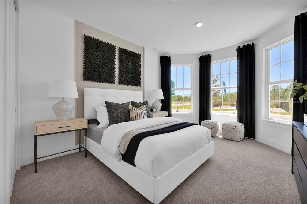A bedroom features a white tufted bed, black wall art, and windows with black curtains — 82 LAKE MANATEE DRIVE, PALM COAST, FL