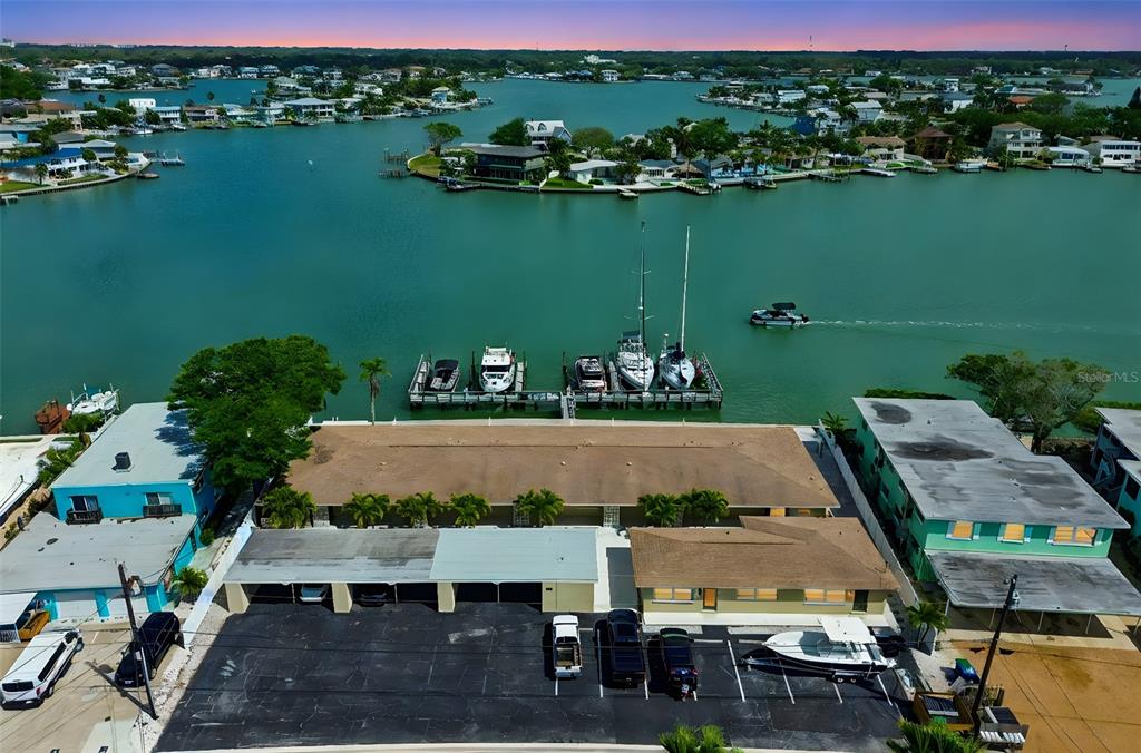 An aerial view shows a waterfront apartment building with a parking lot and boat slips — 2307 BAY BOULEVARD, INDIAN ROCKS BEACH, FL
