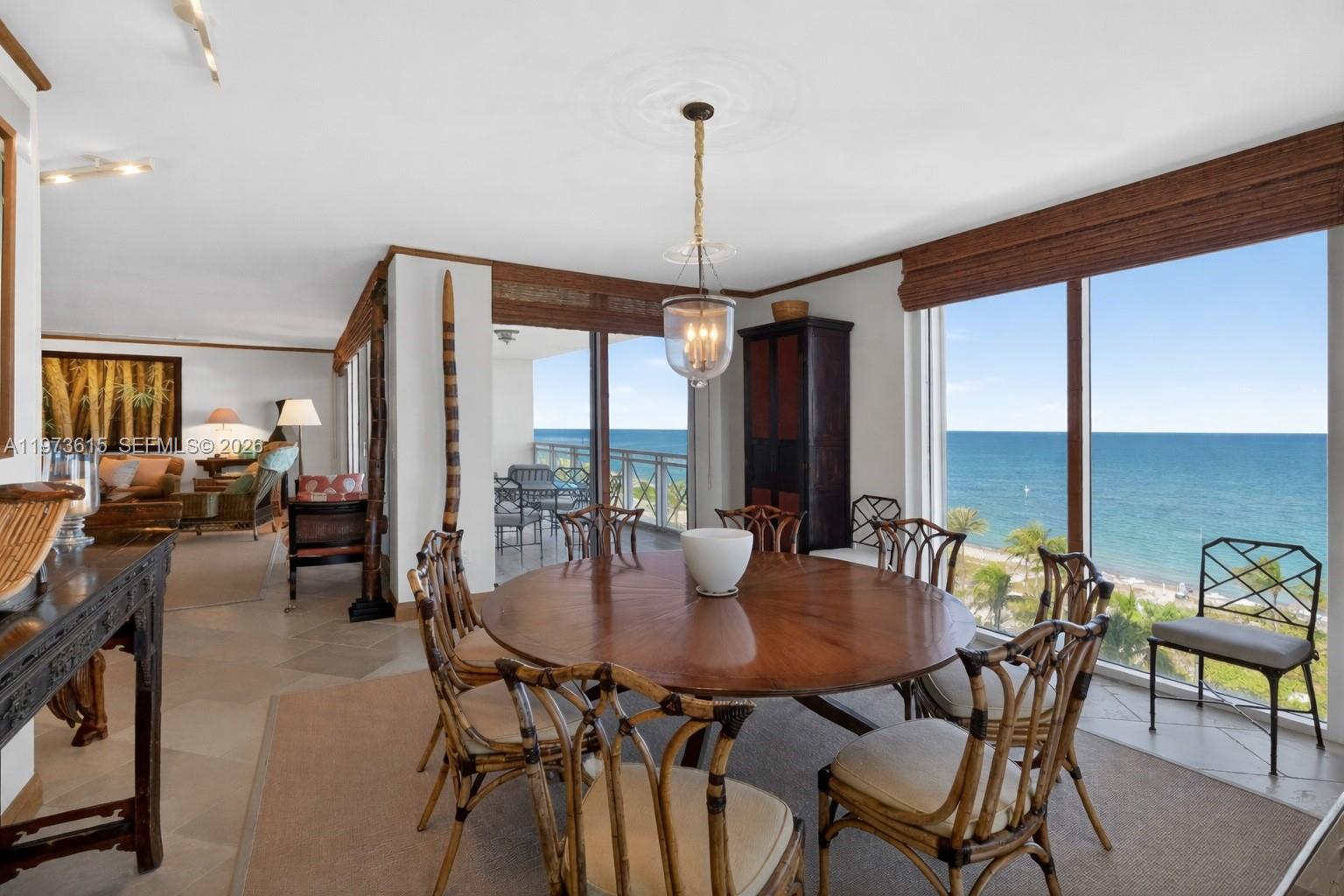 A dining room with a round wooden table, bamboo-style chairs, and floor-to-ceiling ocean views — 430 Grand Bay Dr # 801, Key Biscayne FL 33149, KEY BISCAYNE, FL