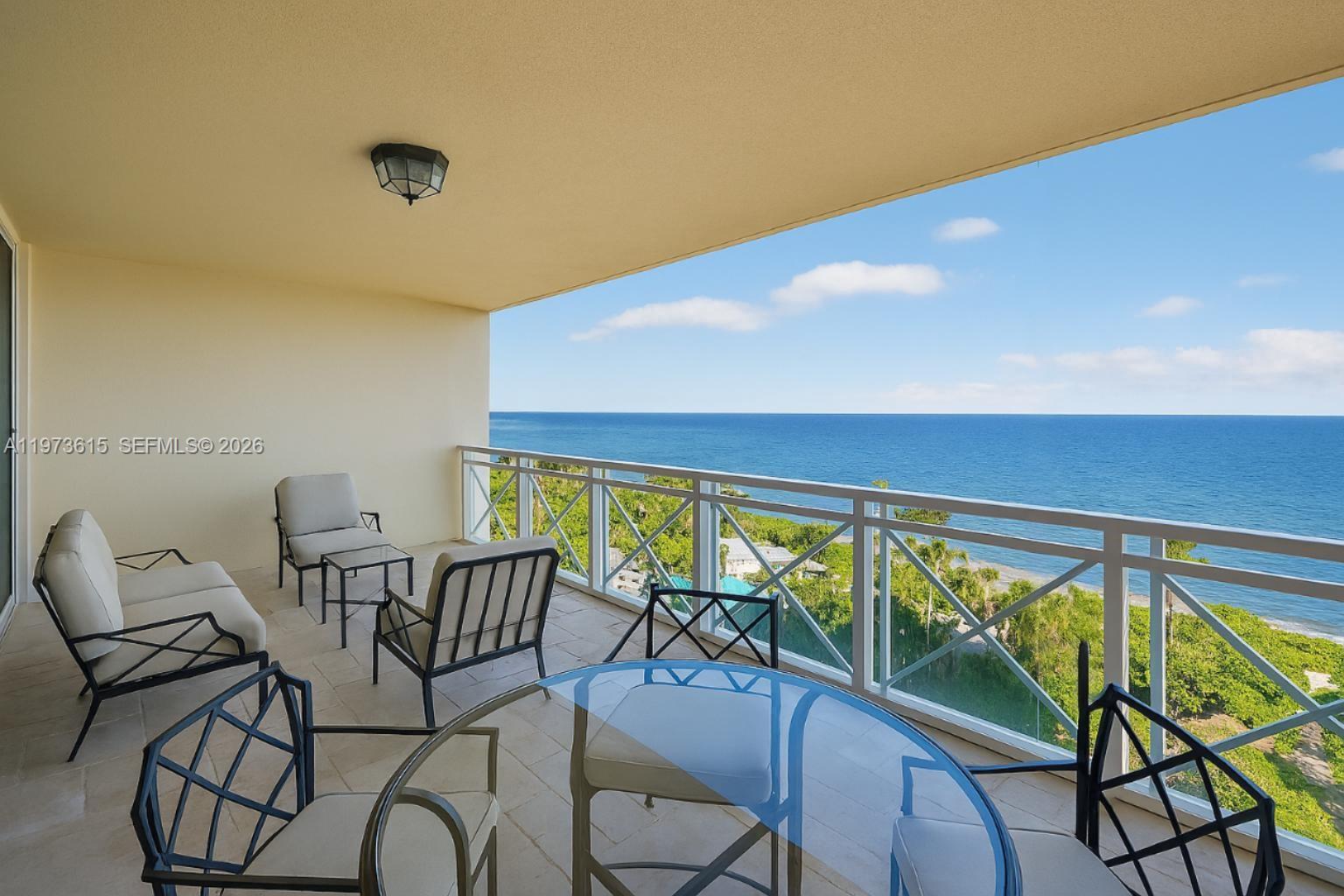 A balcony with patio furniture overlooks the ocean and lush greenery — 430 Grand Bay Dr # 801, Key Biscayne FL 33149, KEY BISCAYNE, FL