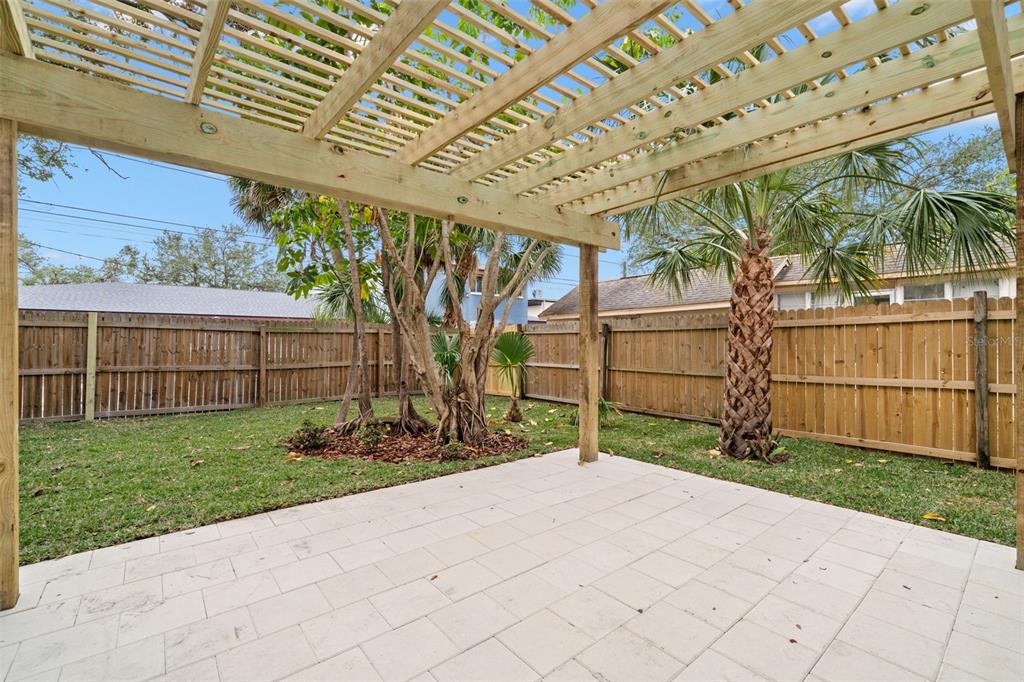 A backyard patio features a wooden pergola over light-colored pavers and a wooden privacy fence — 4536 1ST AVENUE N, ST PETERSBURG, FL