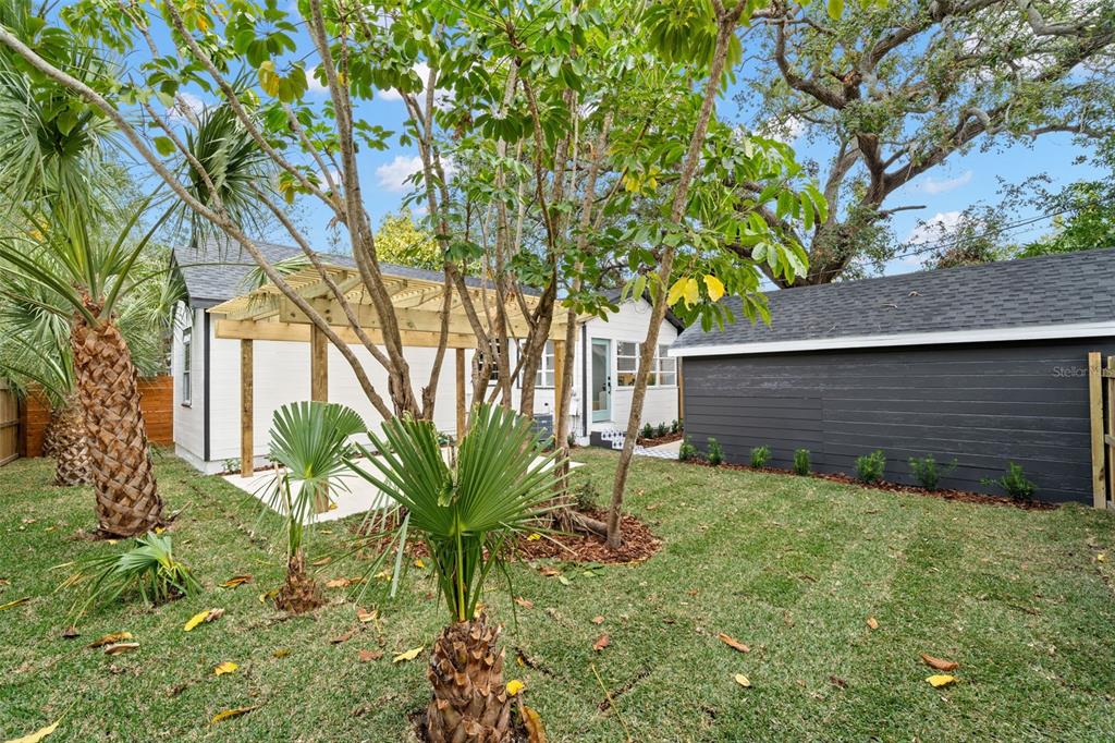 A backyard features a white house with a wooden pergola, a dark garage, and palm trees — 4536 1ST AVENUE N, ST PETERSBURG, FL