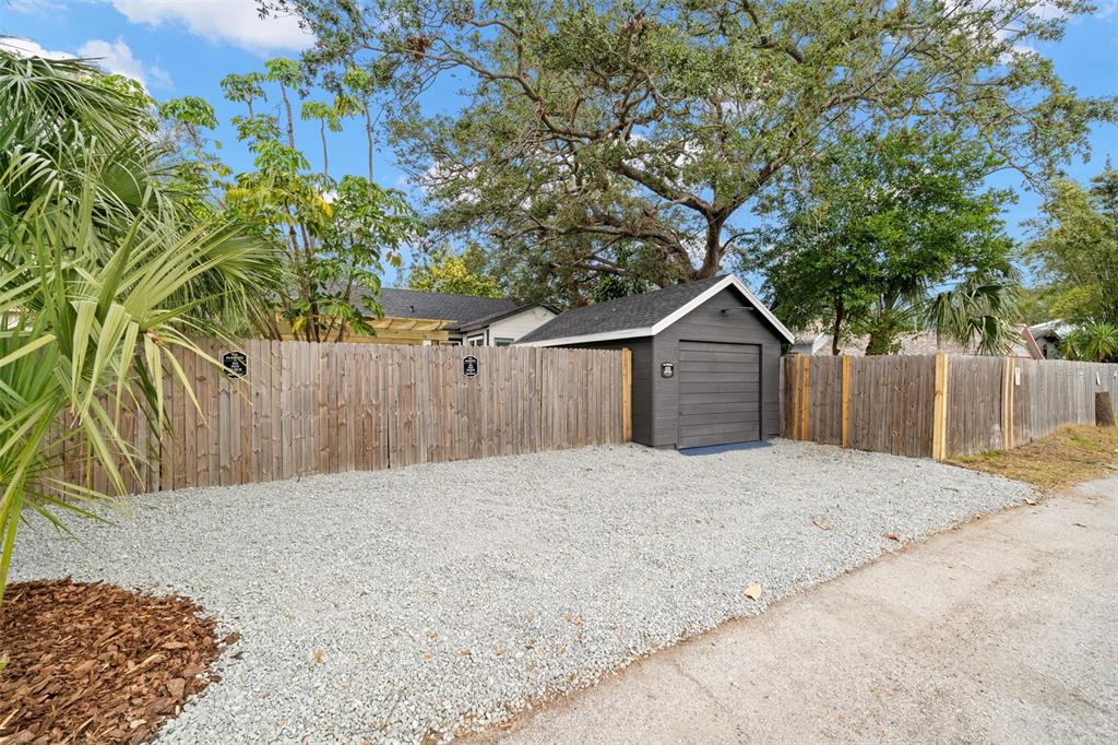 A gravel driveway leads to a detached gray garage behind a wooden privacy fence — 4536 1ST AVENUE N, ST PETERSBURG, FL