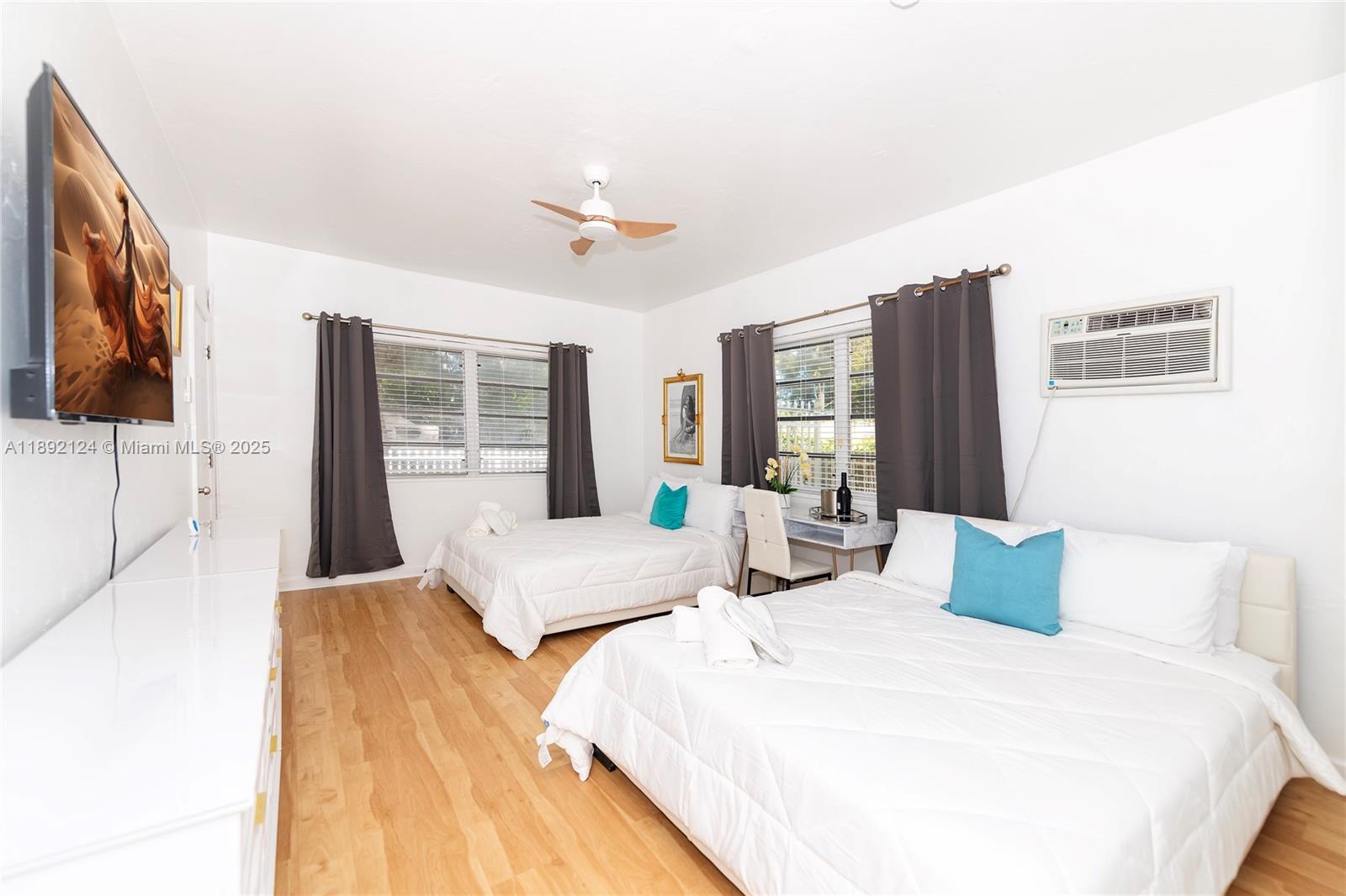 This bedroom features two beds, light wood flooring, a ceiling fan, and a wall-mounted television — 545 Michigan Ave # 2, Miami Beach FL 33139, MIAMI BEACH, FL