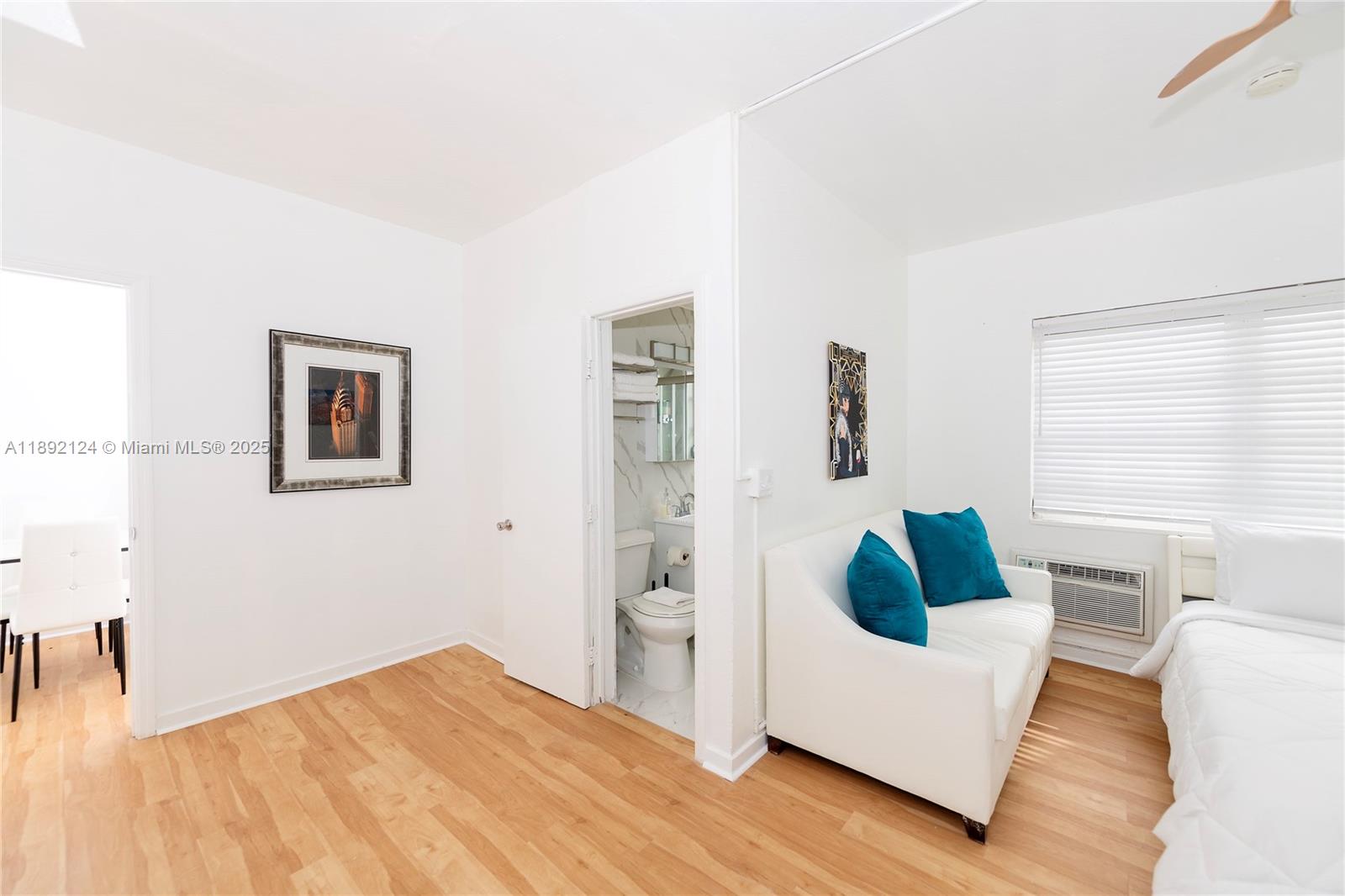 A room features light wood flooring, a white sofa with blue pillows, and a bathroom — 545 Michigan Ave # 2, Miami Beach FL 33139, MIAMI BEACH, FL