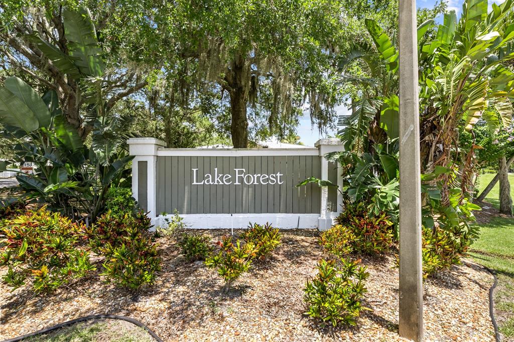 A sign reading Lake Forest stands in a landscaped garden with trees and shrubs — 39 LAKE FOREST PLACE, PALM COAST, FL