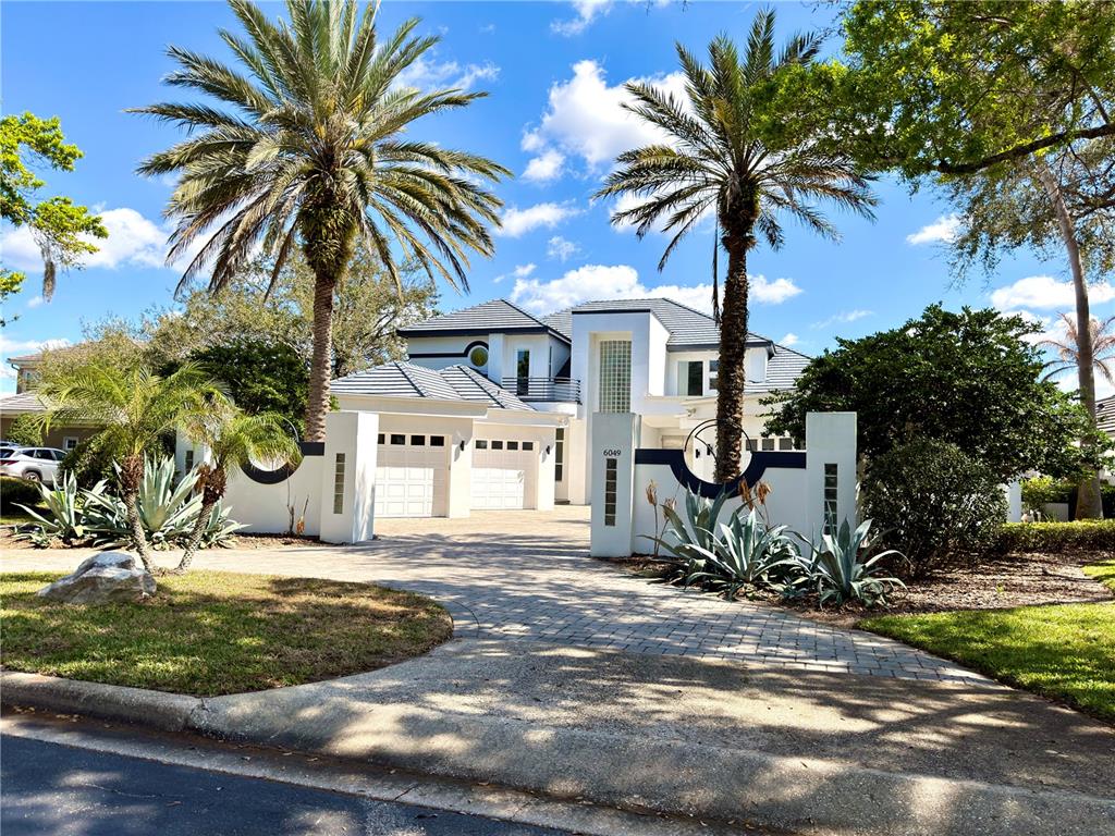 A two-story white house with a paved driveway, palm trees, and a gated entrance — 6049 LADY BET DRIVE, ORLANDO, FL