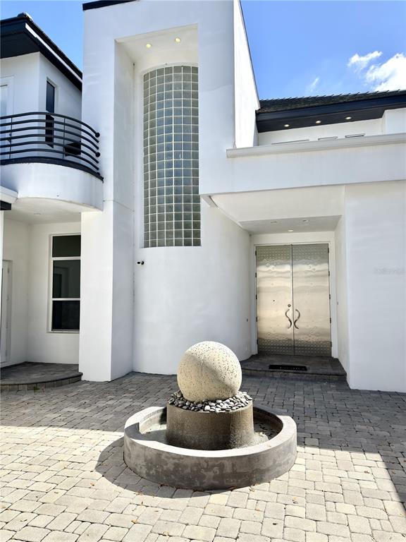 A modern white house exterior features a spherical stone fountain in a paved courtyard — 6049 LADY BET DRIVE, ORLANDO, FL