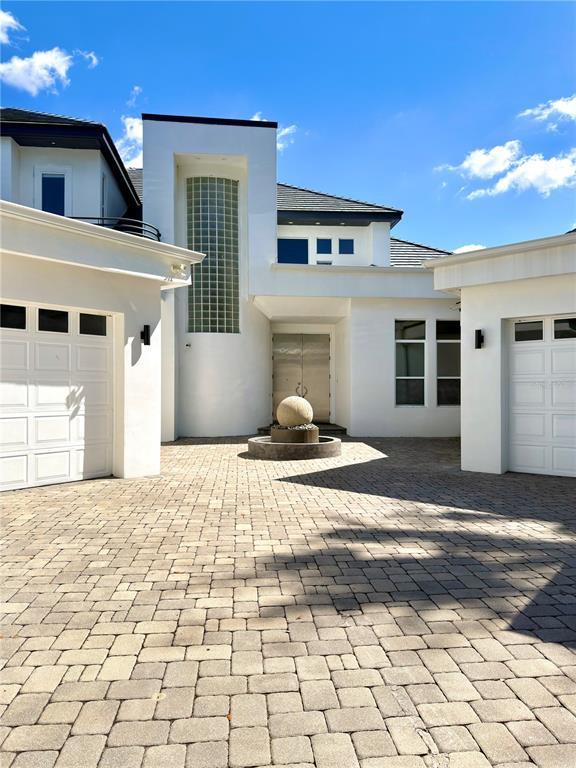 The exterior of a modern white house features a paved driveway and a central fountain — 6049 LADY BET DRIVE, ORLANDO, FL