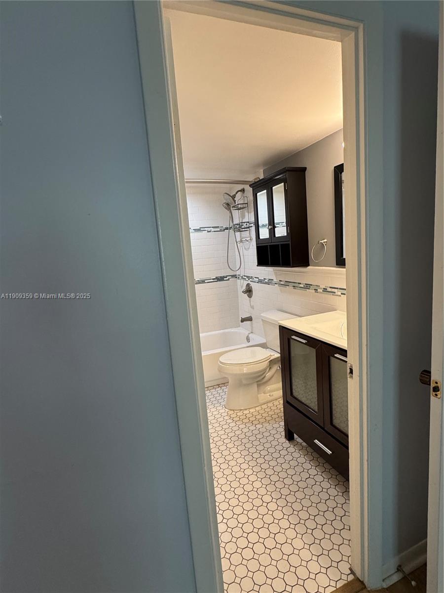 A bathroom features a white tiled shower, a dark wood vanity, and hexagonal floor tiles — 8411 NW 8th St # 203, Miami FL 33126, MIAMI, FL