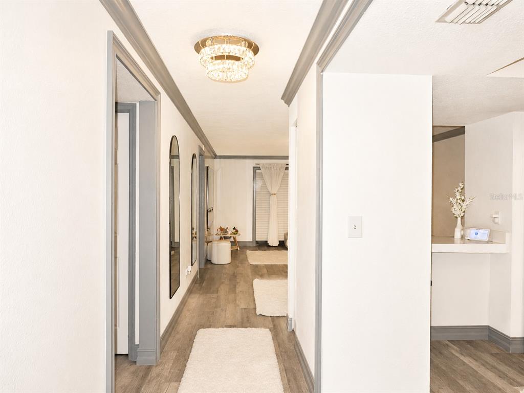 A hallway with gray trim, wood-look flooring, and a crystal flush-mount light fixture — 6301 58TH STREET N UNIT 402, PINELLAS PARK, FL