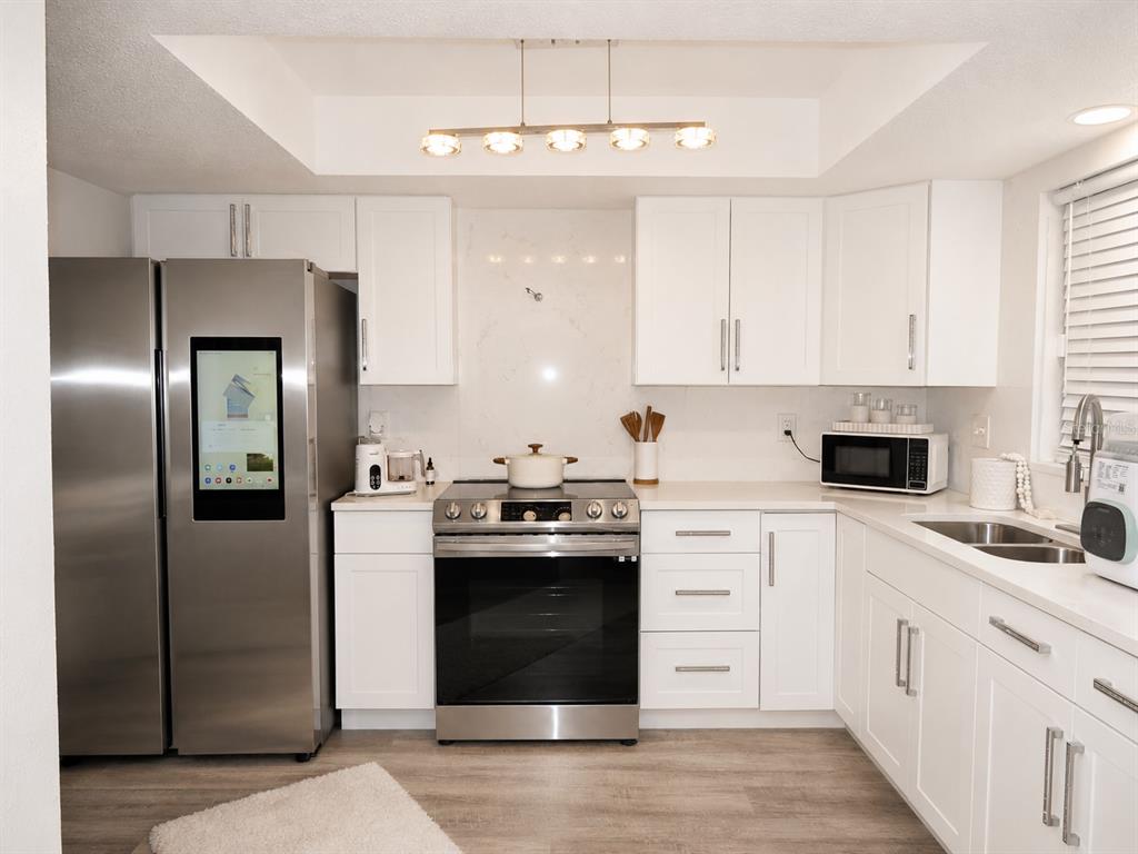 A kitchen with white cabinets, stainless steel appliances, and a smart refrigerator — 6301 58TH STREET N UNIT 402, PINELLAS PARK, FL