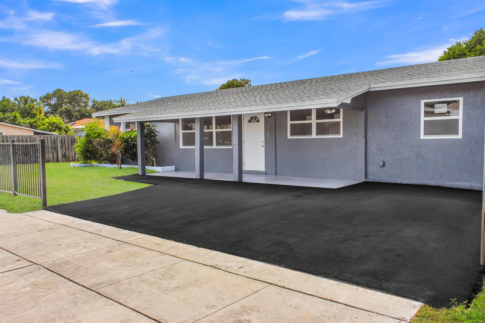 A gray single-story house features a covered front porch and a freshly paved asphalt driveway — 915 SW 3rd Street, Boynton Beach FL 33435, BOYNTON BEACH, FL