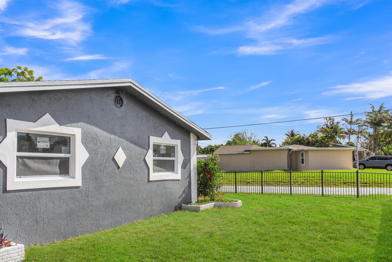 A gray house with white decorative window trim stands beside a fenced grassy yard — 915 SW 3rd Street, Boynton Beach FL 33435, BOYNTON BEACH, FL