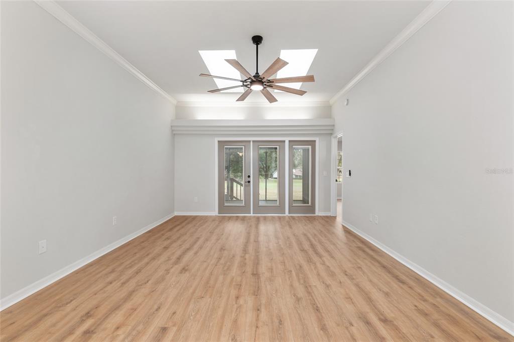 A room with wood-look flooring, a ceiling fan, and a set of glass doors — 6245 NW 106TH PLACE, ALACHUA, FL