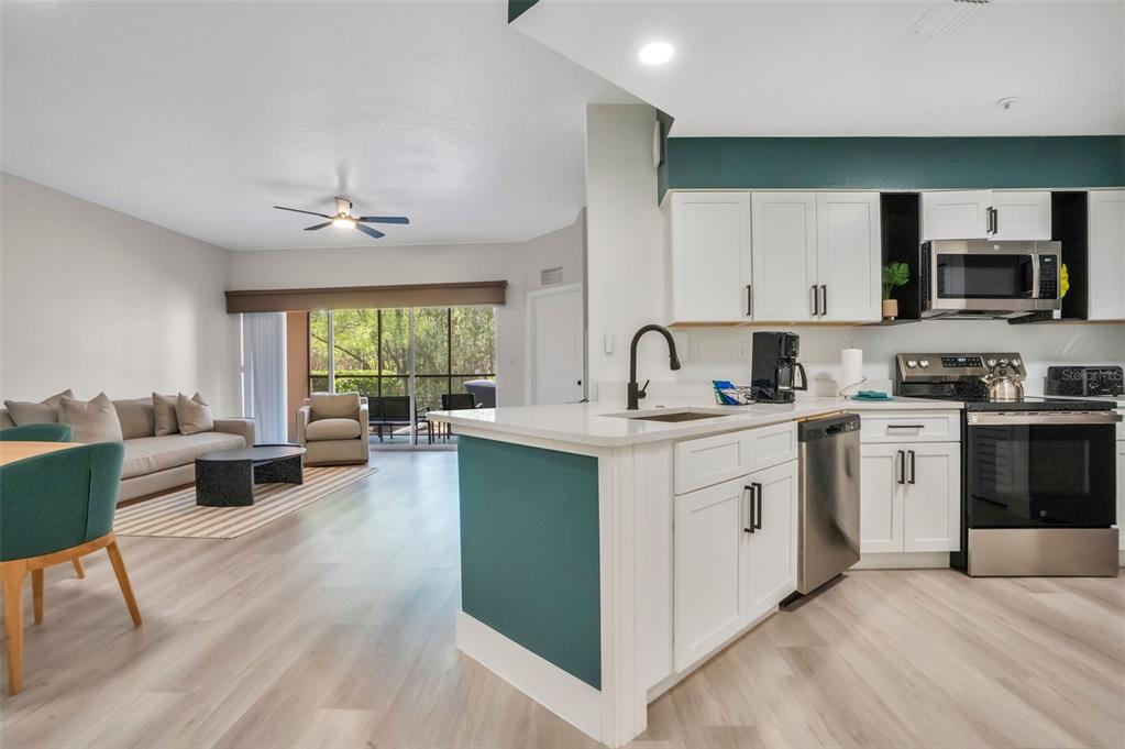 A kitchen with white cabinets and a teal island opens into a living area — 8763 WORLDQUEST BOULEVARD UNIT 5105, ORLANDO, FL