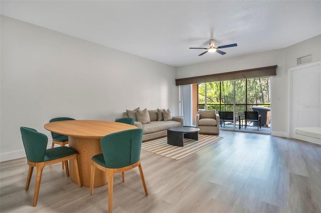 A living and dining area features light wood flooring, a round table, and a sofa — 8763 WORLDQUEST BOULEVARD UNIT 5105, ORLANDO, FL