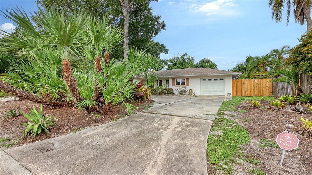 A single-story house with a concrete driveway, palm trees, and a security sign in front — 4735 REMINGTON DRIVE, SARASOTA, FL