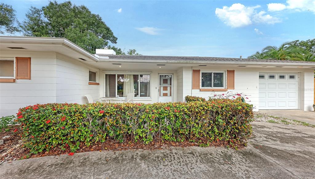 A single-story house with a white exterior, a hedge in front, and a garage — 4735 REMINGTON DRIVE, SARASOTA, FL