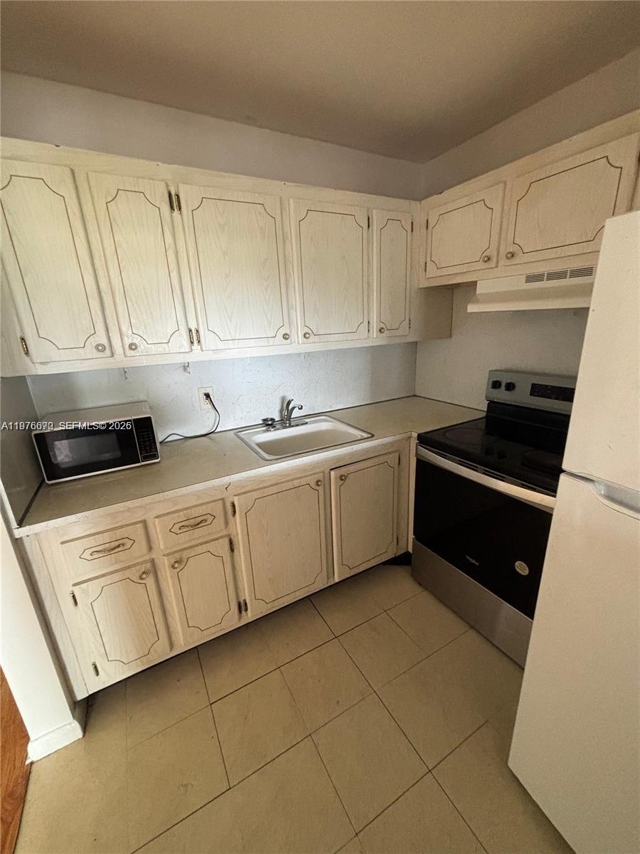 A kitchen features light-colored wood cabinets, a white sink, and a black electric stove — 36 Windsor # B, West Palm Beach FL 33417, WEST PALM BEACH, FL