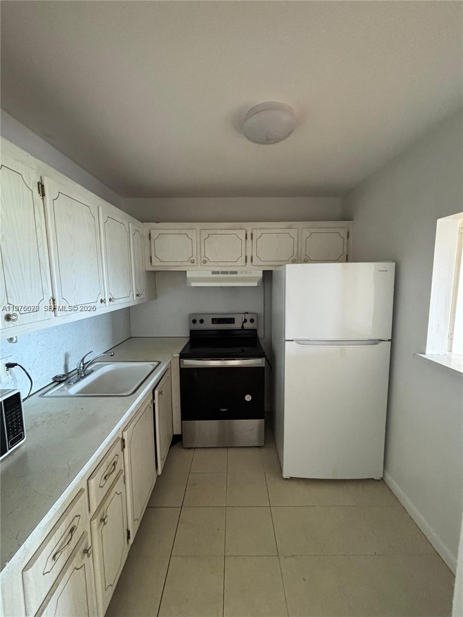 A galley-style kitchen features white cabinets, a stainless steel stove, and a white refrigerator — 36 Windsor # B, West Palm Beach FL 33417, WEST PALM BEACH, FL