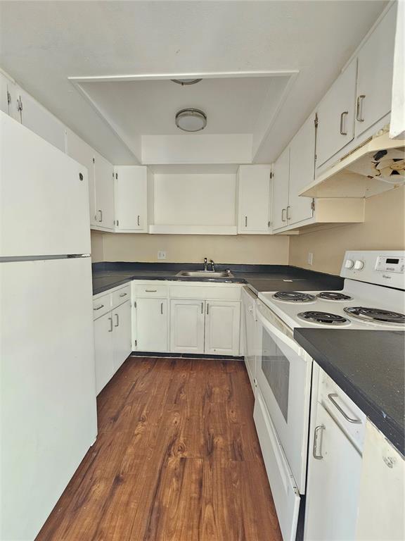 A galley kitchen features white cabinets, black countertops, white appliances, and wood-look flooring — 7611 PAULA DRIVE UNIT 5, TAMPA, FL