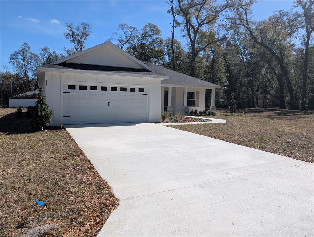 A white single-story house with a two-car garage and a concrete driveway — 1303 NE 23RD AVENUE, OCALA, FL