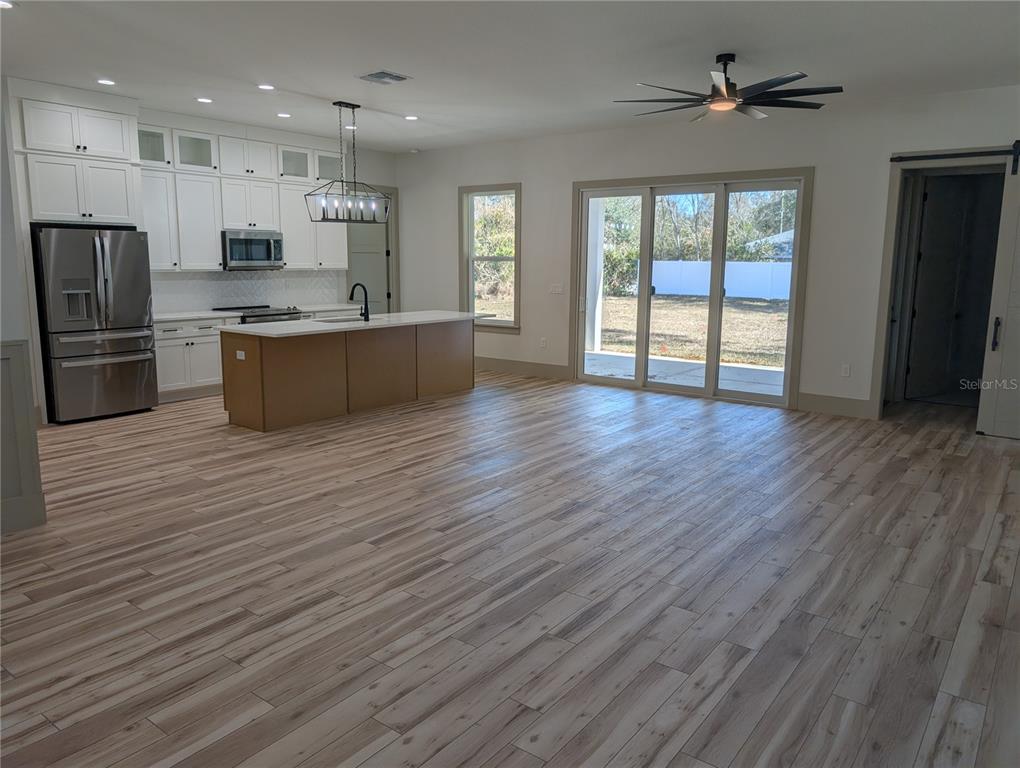 An open-concept kitchen and living area features white cabinetry, a kitchen island, and wood-look flooring — 1303 NE 23RD AVENUE, OCALA, FL