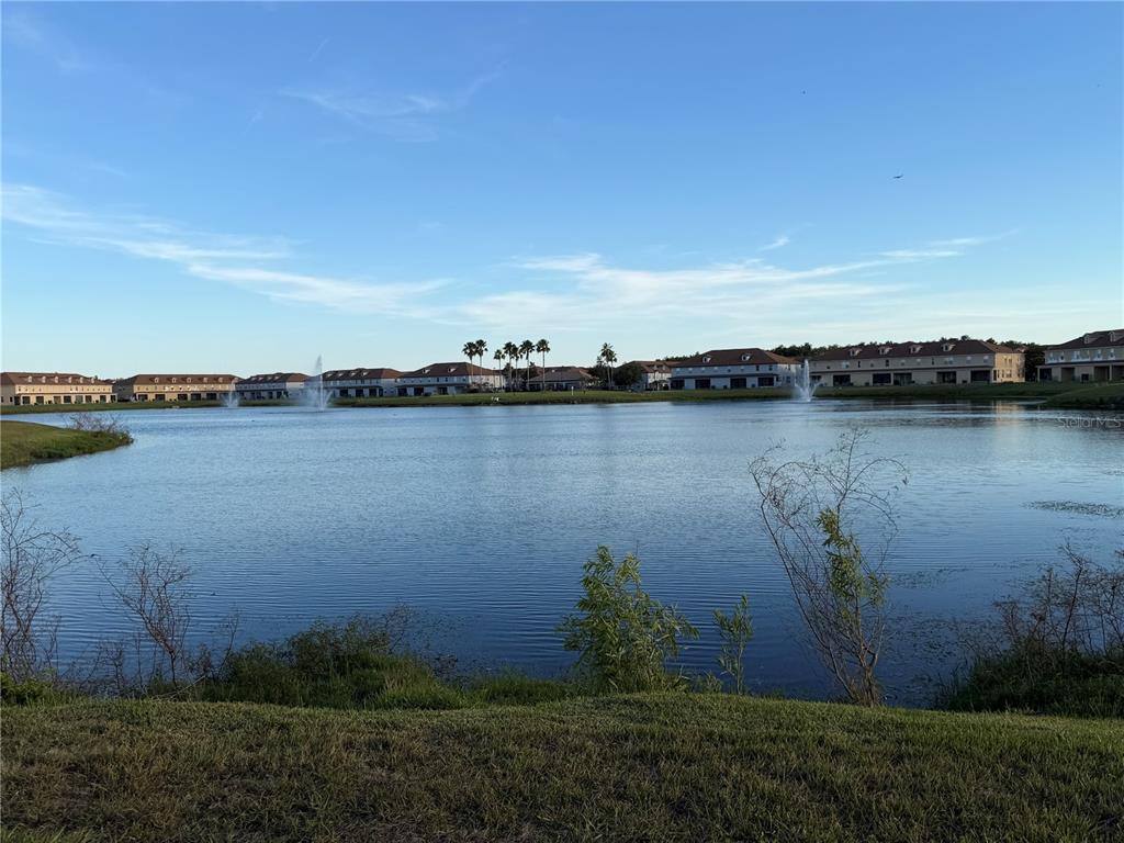 A view of a lake with fountains and residential buildings in the background — 3001 LAUREL RUN LANE UNIT 104, KISSIMMEE, FL