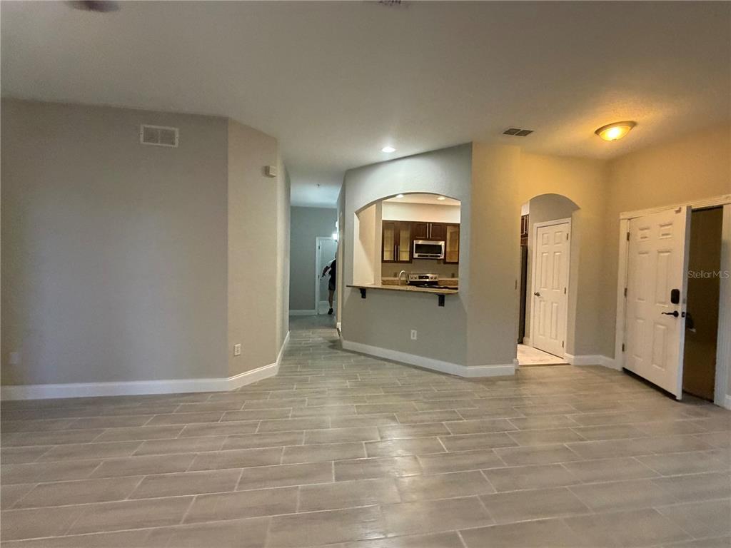 An interior view shows a tiled living area with a kitchen pass-through and entryway — 3001 LAUREL RUN LANE UNIT 104, KISSIMMEE, FL