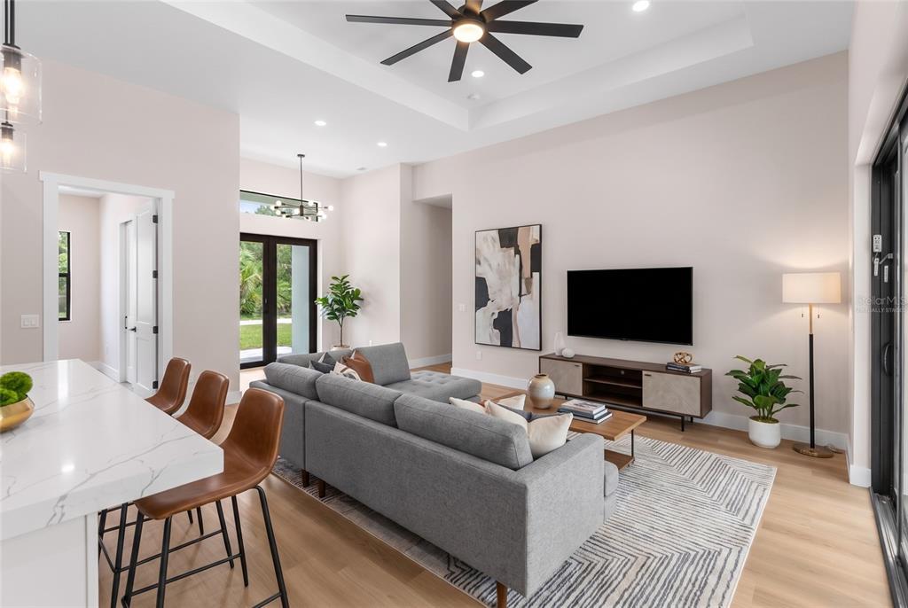 A modern living room features a gray sectional sofa, a television, and a kitchen island — 150 HEATHER STREET, PORT CHARLOTTE, FL