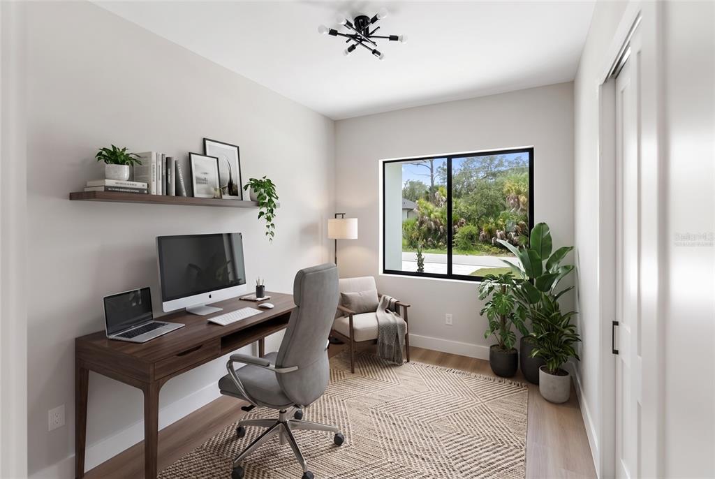A home office features a wooden desk, gray chair, area rug, and a large window — 150 HEATHER STREET, PORT CHARLOTTE, FL