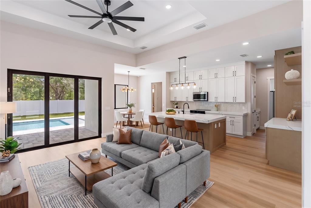 An open-concept living room and kitchen feature a gray sectional, kitchen island, and pool view — 150 HEATHER STREET, PORT CHARLOTTE, FL