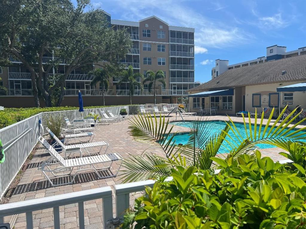 A swimming pool with lounge chairs sits in front of a multi-story apartment building — 960 STARKEY ROAD UNIT 10305, LARGO, FL