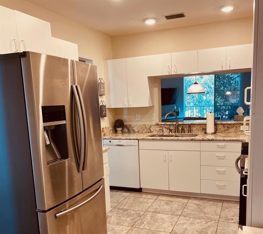 A kitchen features white cabinets, granite countertops, stainless steel appliances, and tile flooring — 9630 CLUB SOUTH CIRCLE UNIT 6201, SARASOTA, FL