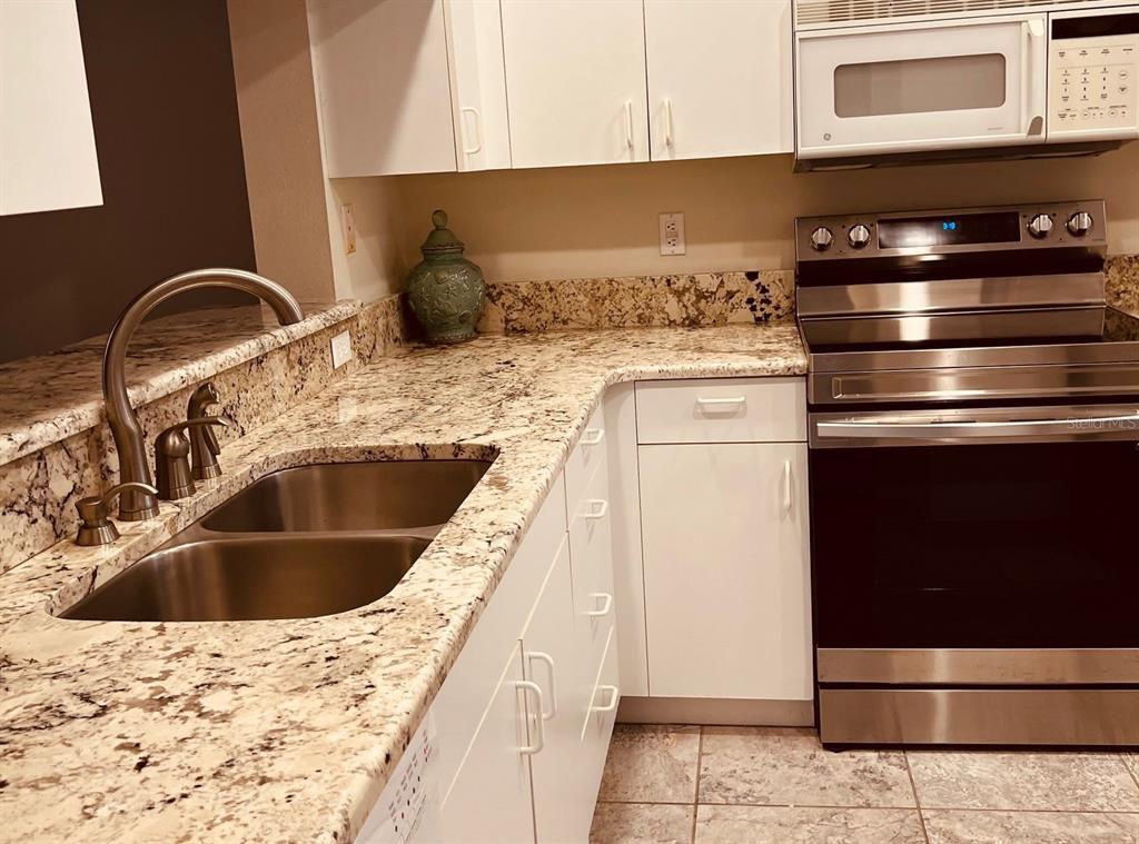 A kitchen features white cabinets, granite countertops, a stainless steel sink, and stainless steel appliances — 9630 CLUB SOUTH CIRCLE UNIT 6201, SARASOTA, FL