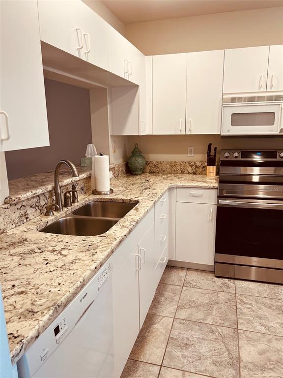 A kitchen features white cabinets, granite countertops, stainless steel appliances, and tiled flooring — 9630 CLUB SOUTH CIRCLE UNIT 6201, SARASOTA, FL